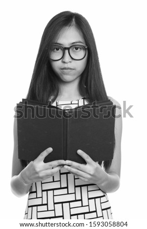 Close up of young Asian teenage nerd girl holding book