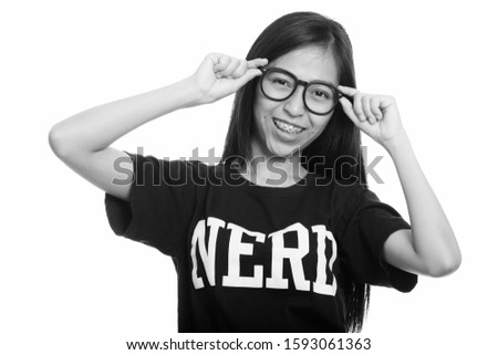 Studio shot of young happy Asian teenage nerd girl smiling while holding eyeglasses