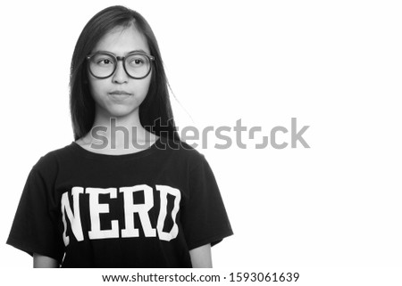 Studio shot of young Asian teenage nerd girl thinking