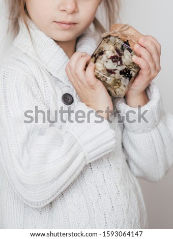 Stock Photo -  Beautiful little girl with jars in which honey and nuts with wooden christmas decor