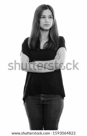 Studio shot of young beautiful woman standing and thinking with arms crossed