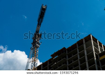 Photo of a multi-storey building under construction. Construction of a residential skyscraper. Background image of the process of building a house with cranes.