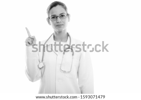 Studio shot of young beautiful woman doctor pointing finger up