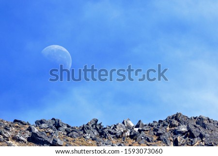 Beautiful landscape view of the moon rising over a horizon of stones.