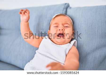 Adorable baby lying down on the sofa at home. Newborn crying and screaming