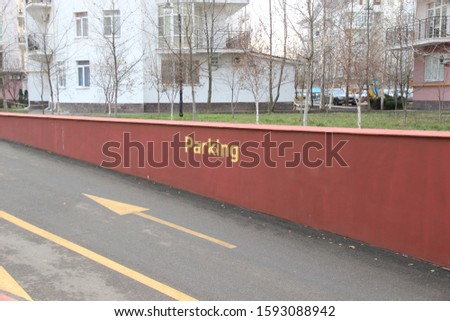 Red fence at the entrance to the underground Parking lot with asphalt road and yellow markings