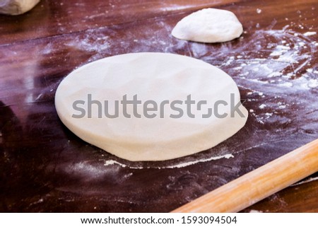 pictured in the photo a piece of dough and a rolling pin on the table