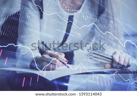 Double exposure of hands making notes with forex chart huds. Stock market concept.
