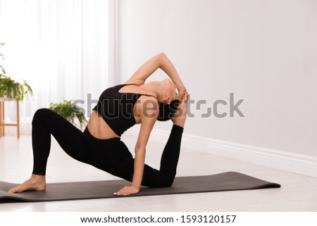 Professional young acrobat practicing yoga at home