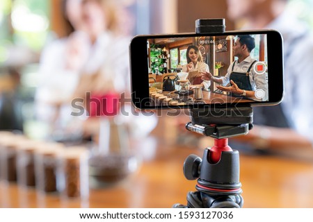 VLOG of  young adult asian owner entrepreneur review cafe coffee shop and live in social media for online marketing with smart phone in cafe. Startup of small business marketing consumerism concept Royalty-Free Stock Photo #1593127036