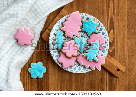 Home-cooked ginger christmas cookies with pink and blue sugar icing on a plate. Warm home baking