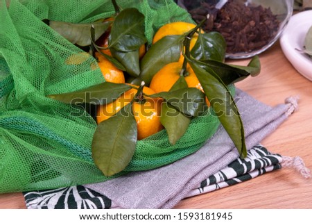 Composition of fresh mandarins with linen and reusable bags, wooden plates and glass jars.