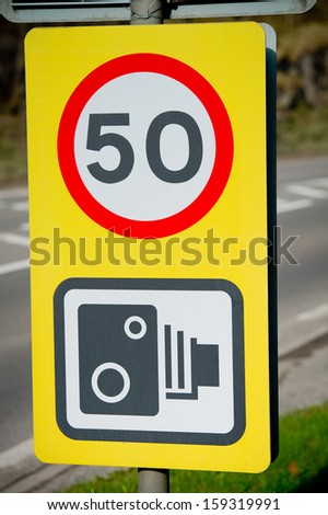 50 miles speed limit and black and white speed camera warning sign
