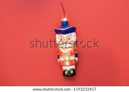 Glass Christmas toy fabulous Christmas nutcracker in a soldier's uniform on a red background.