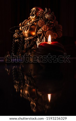 Buddha figurine with a candle on a glass table. Empty copy space. 
