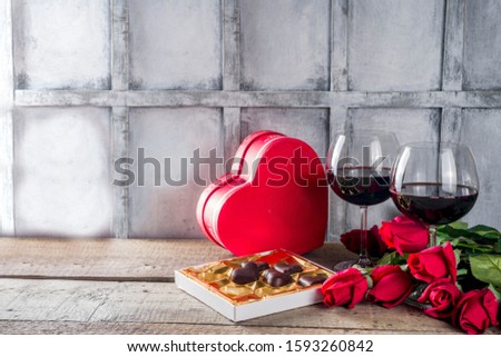Valentines day with red roses and  heart shaped chocolates and wine in glasses on wooden table. Copy space for your text