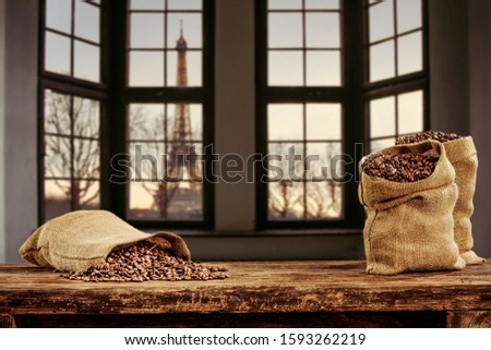Fresh coffee beans in sacks on wooden old table.Home interior with big window and city landscape.Morning time and copy space. 