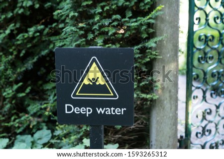 warning sign in black and yellow indicating the danger of drowning in deep water forbidding people to swim, english language