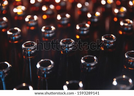 Glass bottles of beer on dark background. Concept brewery plant production line.