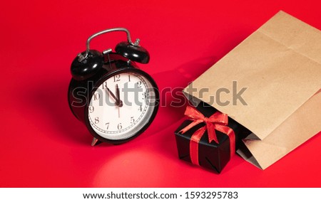 Top view of gift box with red ribbons, shopping paper bag and clock isolated on red background. Shopping concept boxing day and black Friday sale composition.