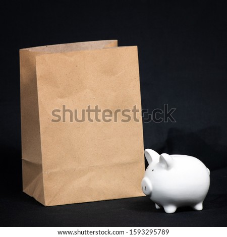 Composition with piggy bank and shopping paper bag isolated on black background. Space for text
