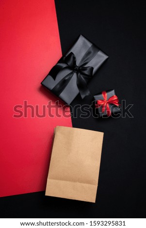 Top view of gift box with red, shopping paper bag, black ribbons and piggy bank isolated on red and black background. Shopping concept boxing day and black Friday sale composition.