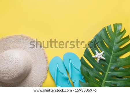 Female beach straw sunhat, outfit, flip flops, tropical monstera on yellow. Top view. Summer travel concept. Top view and space for text.