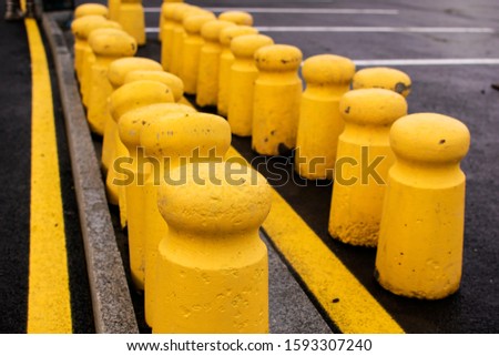 Yellow concrete bollards at a parking lot