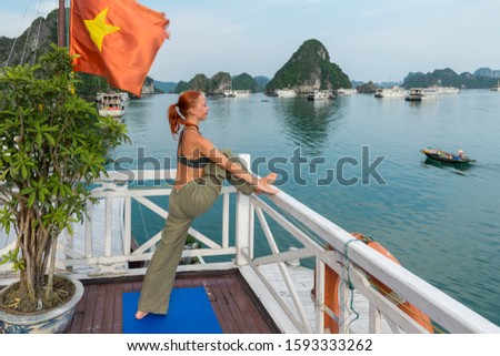 Young woman practicing yoga on the upper deck of ship. Morning time just after sunrise