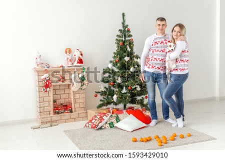 Holidays concept - happy man and woman at christmas tree at home