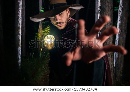Young magician in costuem perform acrobat moves in dark forest