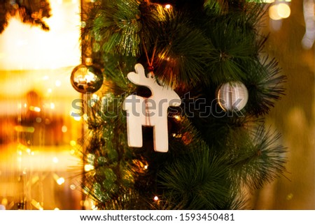 Christmas card with with Christmas toys, fir branches and garland bokeh. Decor from fir branches and New Year's decor with traditional wooden deer, golden balls and bright lights of garlands. Blurry