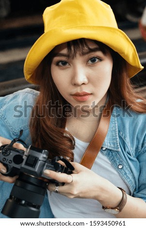 Portrait image of photographer woman in yellow hat and denim jacket check the photo in her camera.