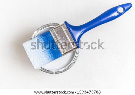 Blue brush and a can of white paint.