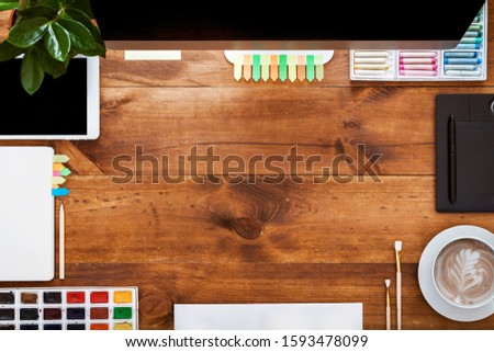 Graphic design modern creative table concept, pc computer monitor and paints digital tablet phone on brown wooden desk with empty mock up copy space for designer work, flat lay, workspace top view