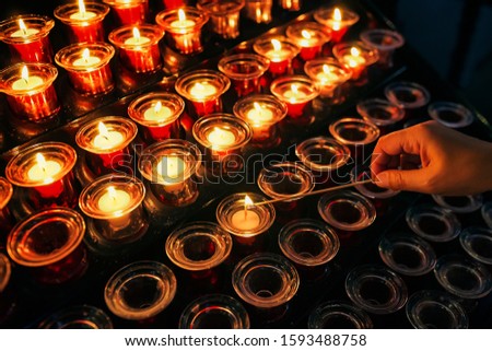 woman lighting a candle in church for his dead relatives
