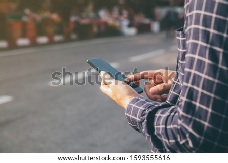 Close-up male hands using smartphone on city shopping street, searching or social networks concept, 