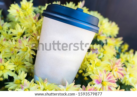 disposable coffee cups placed on a yellow flower with copy space