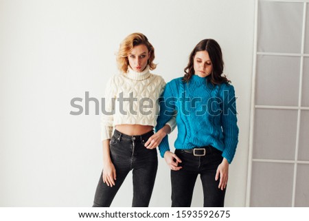 Portrait of two beautiful fashionable blonde women and a brunette in a winter sweater