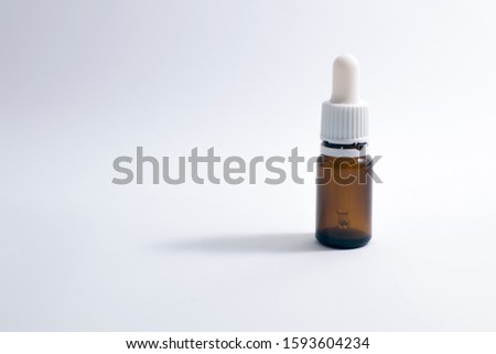 Dark bottle with a dropper. Closed dark bottle with a white cap. Bottle on a white background with a shadow. Bottle for aromatic oils. Royalty-Free Stock Photo #1593604234