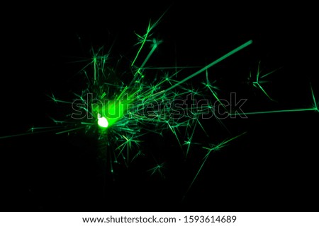 Burning sparkler in green and white light on a black background. Closeup photo of Christmas and new year sparkler