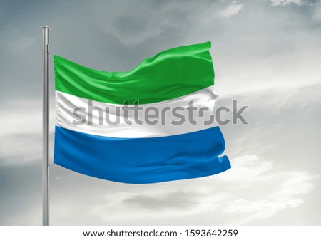 Sierra Leone national flag cloth fabric waving on beautiful grey sky.