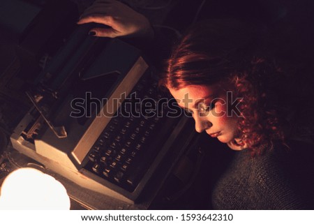 Redhead 
girl sitting next to a typewriter
