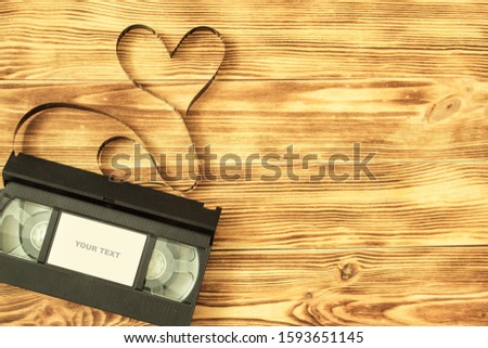 video cassette with unwound film in shape of a heart and with inscription your text, on wooden boards. Theme of Valentine's day, love and wedding. Vintage style background.