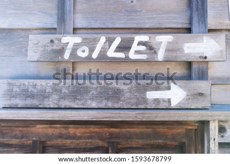 A wooden sign indicating the way to the toilet with an arrow pointing.Vintage Pallet style
