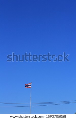 Thai flag on clear blue sky background.