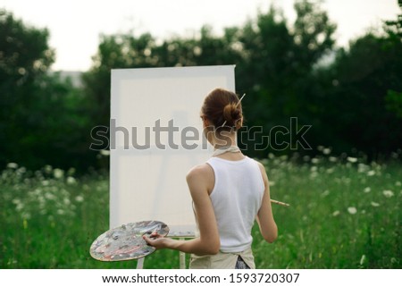 woman easel paints a picture on canvas