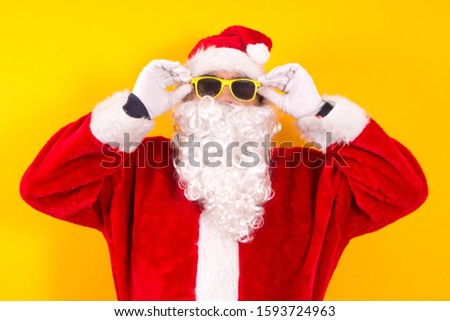 santa claus putting on sunglasses with yellow background