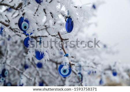 Blue evil eye (nazar boncuğu), Turkish symbols hanging on a frozen tree in winter; Cappadocia, Nevsehir Turkey