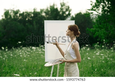 young woman paints a picture on canvas with paints